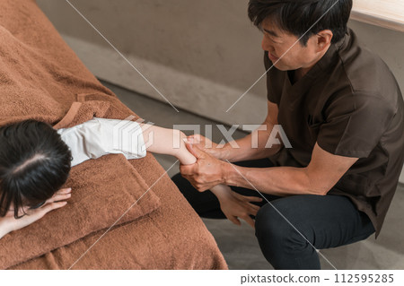 A woman who goes to a chiropractic clinic/osteopathic clinic/massage and a chiropractor/therapist (arm massage) 112595285