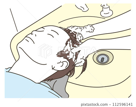 A young man gets shampooed while lying on his back at a shampoo table in a beauty salon A young man gets shampooed while lying on his back at a shampoo table in a beauty salon 112596141