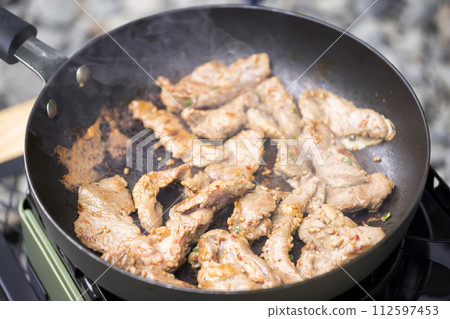 Image of grilling meat in a frying pan at a campsite: Barbecue Image of grilling meat in a frying pan at a campsite: Barbecue 112597453