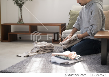 Faceless face of a man doing housework folding laundry, with copy space Faceless face of a man doing housework folding laundry, with copy space 112597575