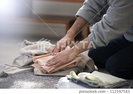 Faceless close-up of a man doing housework folding laundry with copy space Faceless close-up of a man doing housework folding laundry with copy space 112597583