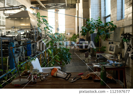 No people interior shot of post-apocalyptic workshop in abandoned building with green plants growing in pots, old computers and tools on tables No people interior shot of post-apocalyptic workshop in abandoned building with green plants growing in pots, old computers and tools on tables 112597677