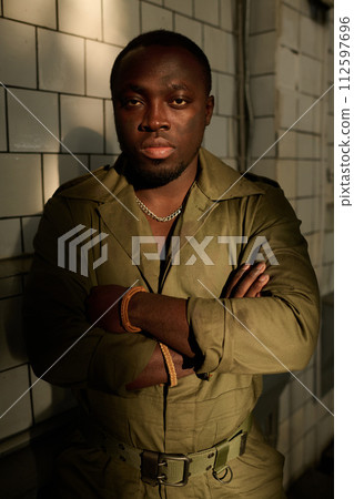 Vertical medium portrait of young African American man with dirt on face and clothes posing for camera with arms crossed 112597696