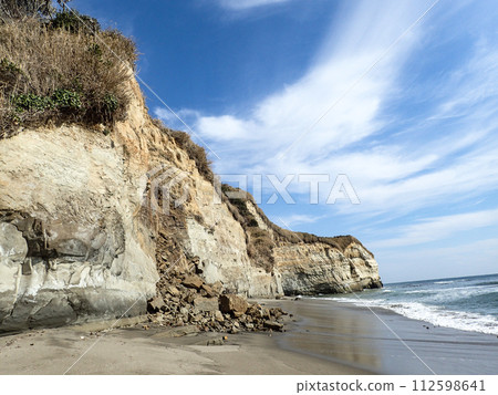 Collapsed rock wall on a sandy beach 112598641