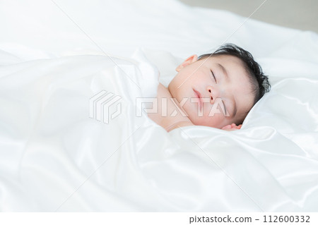 4 month old boy sleeping wrapped in sheets 112600332