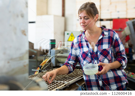 Woman planting seeds into seedling tray in agricultural facility Woman planting seeds into seedling tray in agricultural facility 112600416