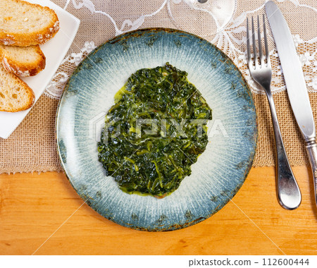 Spinach salad with raisins and pine nuts 112600444
