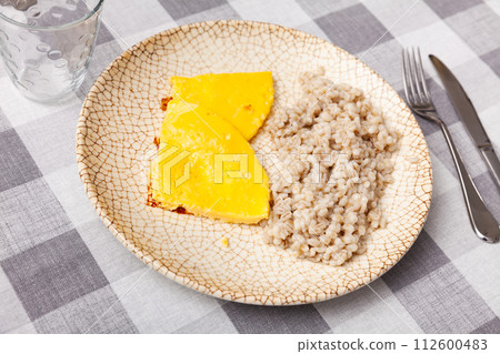 Boiled pearl barley with omelette served on dish on checkered cloth Boiled pearl barley with omelette served on dish on checkered cloth 112600483