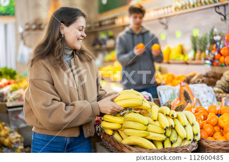 Young woman choosing bananas in vegetable shop Young woman choosing bananas in vegetable shop 112600485