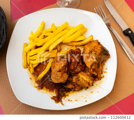 Pollo rustido in Catalan - baked chicken flavored with oregano, white wine, sweet wine, prunes. Served with French fries 112600612