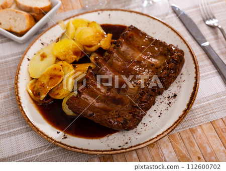 Baked under sauce pork ribs at plate with potatoes Baked under sauce pork ribs at plate with potatoes 112600702