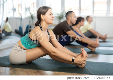 People doing yoga position while sitting on floor in modern sport club People doing yoga position while sitting on floor in modern sport club 112600933