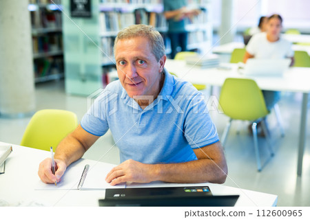 Elder male worker researching with a laptop Elder male worker researching with a laptop 112600965