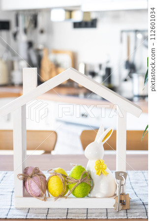 Key and tiny house of cozy home with Easter decor with rabbit and eggs on table of kitchen. Building, design, project, moving to new house, mortgage, insurance, rent and purchase real estate Key and tiny house of cozy home with Easter decor with rabbit and eggs on table of kitchen. Building, design, project, moving to new house, mortgage, insurance, rent and purchase real estate 112601034