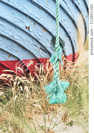 Rope of old fishing boat lying on the beach in Denmark 112601100