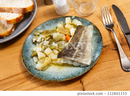 There is plate with fried cod fillet and braised french green bean on wooden table. There is plate with fried cod fillet and braised french green bean on wooden table. 112601153