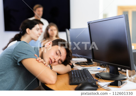 Exhausted young employee engaged in software development sleeping at workplace 112601330