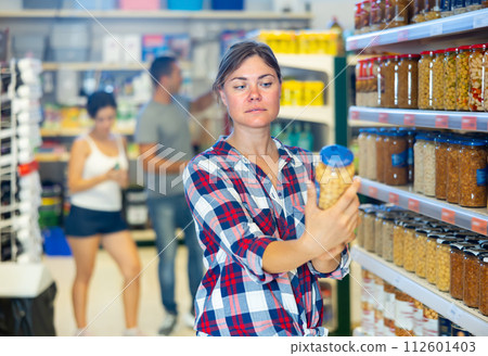 Young woman choosing canned beans in sauce in supermarket Young woman choosing canned beans in sauce in supermarket 112601403