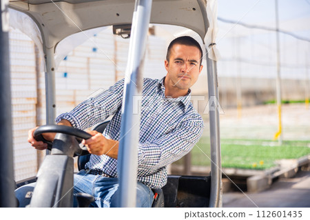 Attentive farmer man working on forklift loader at farm greenhouse Attentive farmer man working on forklift loader at farm greenhouse 112601435