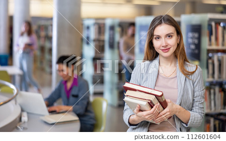 Portrait of woman holding books at library 112601604