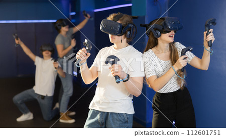 Young guy and girl in vr headset stand shoulder to shoulder interacting with digital interface Young guy and girl in vr headset stand shoulder to shoulder interacting with digital interface 112601751