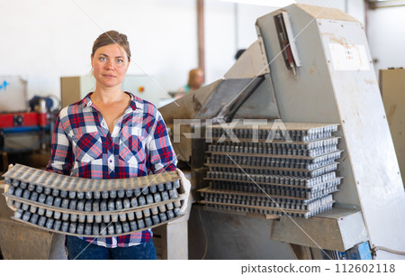 Woman carrying cell seed trays in agricultural facility 112602118