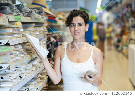 Woman choosing slippers in supermarket Woman choosing slippers in supermarket 112602140