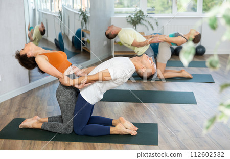 Two young people yogi doing balance back stretch acro yoga pose at sport gym. Healthy lifestyle modern activity 112602582