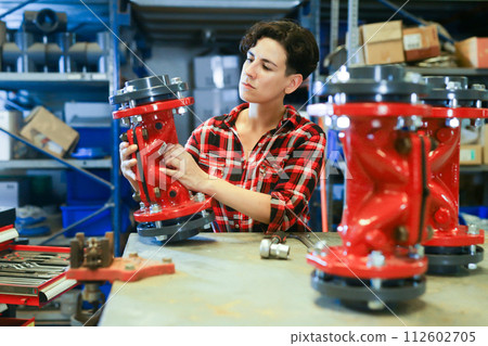 Woman assembling plumbing fixture in workshop Woman assembling plumbing fixture in workshop 112602705