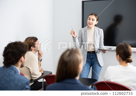 Young female professor explaining subject to classroom full of students Young female professor explaining subject to classroom full of students 112602733