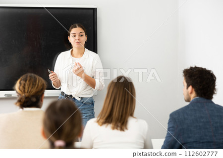 Young female professor explaining subject to classroom full of students Young female professor explaining subject to classroom full of students 112602777