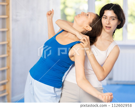 Woman makes a choke hold in self defense trainin 112602958