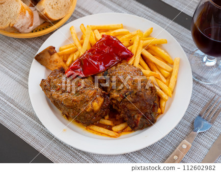Stewed in sauce pork knuckle with baked peppers and french fries 112602982