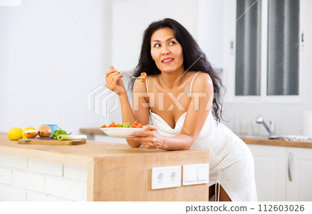 Portrait of woman eating salad at home Portrait of woman eating salad at home 112603026