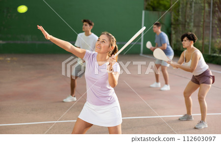 Young Latina playing pelota on open court on summer day Young Latina playing pelota on open court on summer day 112603097