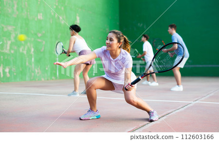 Woman serving ball during frontenis game outdoors Woman serving ball during frontenis game outdoors 112603166