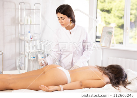 female doctor making butt beauty procedure with macro molecule atomizing pen 112603243