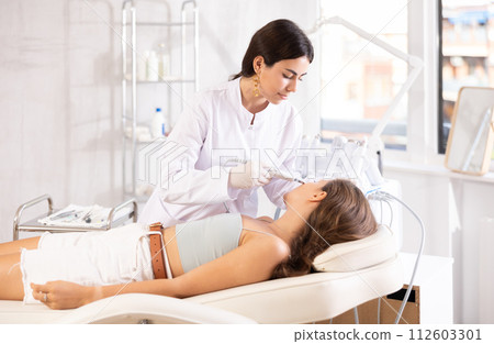 Female cosmetologist performing facial skin cleansing with ultrasonic shovel on woman Female cosmetologist performing facial skin cleansing with ultrasonic shovel on woman 112603301