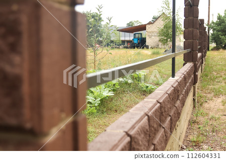 Brown metal profile fence with block posts. Incline construction 112604331