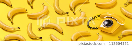 Banner bananas and old yellow phone with hard shadows pattern on yellow background flat lay bananaphone Banner bananas and old yellow phone with hard shadows pattern on yellow background flat lay bananaphone 112604351