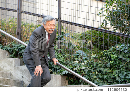 Senior man with knee pain on stairs 112604580