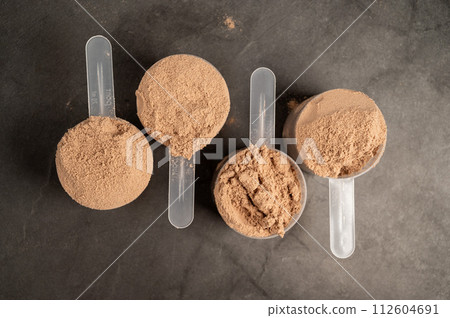 Chocolate protein powder in scoops. Food supplement, nutrition  112604691