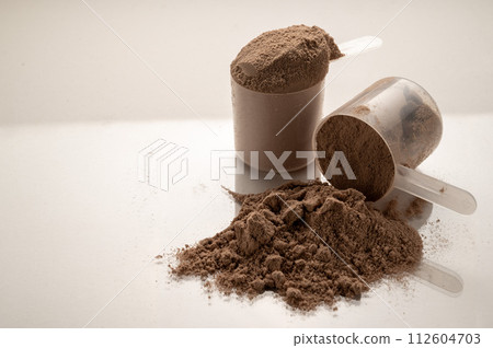 Chocolate protein powder in scoops. Food supplement, nutrition  112604703