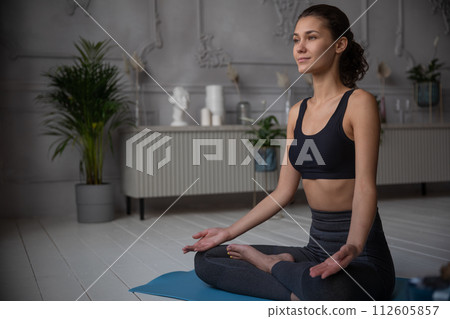 young woman sits at the yoga pose at home young woman sits at the yoga pose at home 112605857