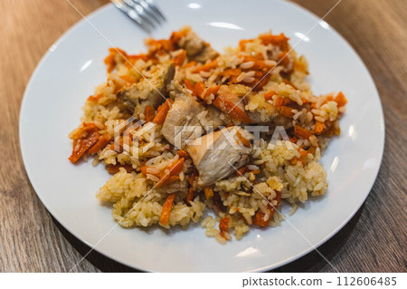 PA plate of delicious Uzbek pilaf served at a charming local restaurant. This traditional Central Asian dish features flavorful rice, tender pieces of meat, and aromatic spices.late of Delicious Uzbek 112606485