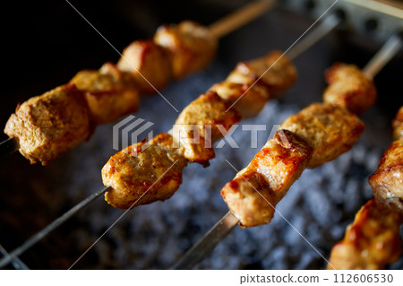 Summer Barbecue at Home Featuring Kebabs Grilling in a Backyard Grill 112606530
