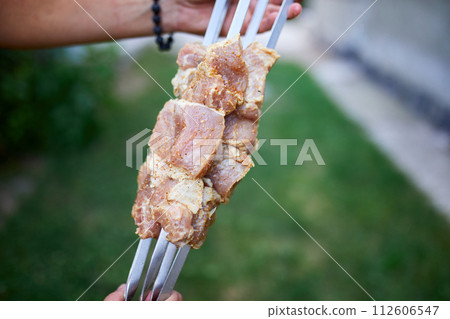 Summer Backyard Barbecue Featuring Hand-Threaded Kebabs Ready for Grilling 112606547