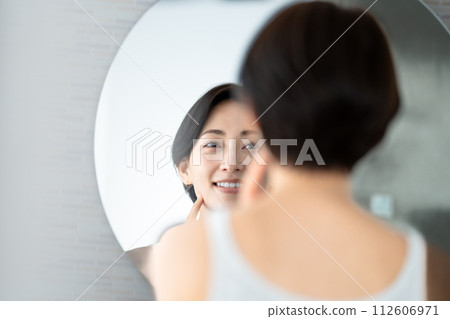 Woman looking in the mirror 112606971
