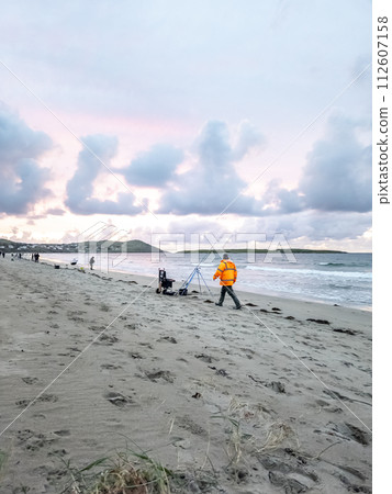 20 man are competing in a fishing competition on the beach. 20 man are competing in a fishing competition on the beach. 112607158