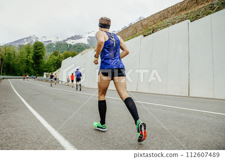 male athlete running last in group runners in mountain marathon race male athlete running last in group runners in mountain marathon race 112607489